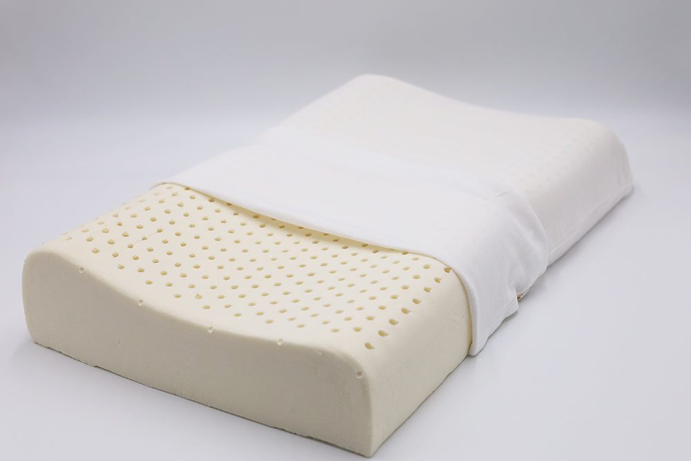 Organic latex contour pillow with pinhole ventilation, shown partially covered in a white cotton case