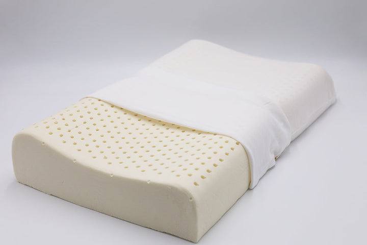 Organic latex contour pillow with pinhole ventilation, shown partially covered in a white cotton case