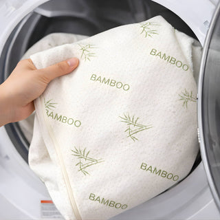 Machine washable bamboo crib mattress topper cover being placed into a washing machine