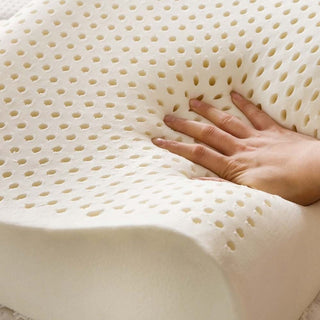 Natural Talalay latex contour pillow displayed outdoors on a cushion, showcasing its wave shape and breathable pinhole design.